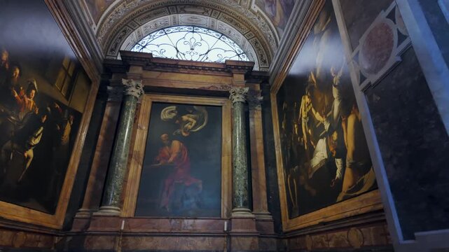 Baroque chapel featuring three Caravaggio paintings framed by marble columns and arched window inside historic Roman church
