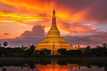 Golden buddhist temple shines during dramatic sunset sky