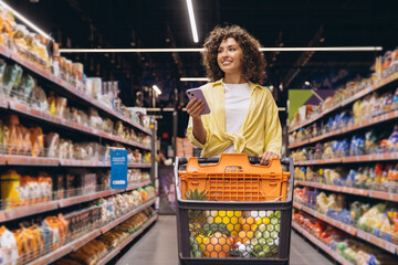 Woman Using Smartphone While Shopping for Groceries in Supermarket