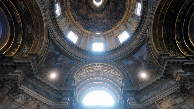 Interior of Sant&rsquo;Agnese in Agone with decorated arches and radiant dome featuring elaborate baroque frescoes and windows