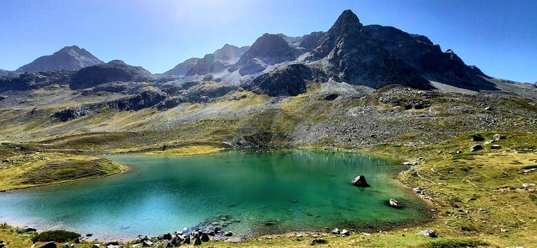 Turquoise blue mountain lake on the Julier Pass in the Swiss mountains in the clear morning sunlight surrounded by lush bright green meadows