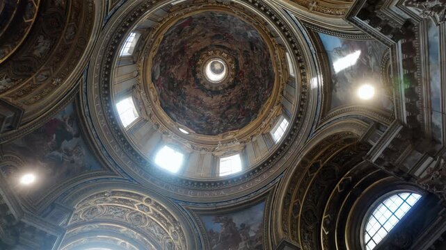Ornate baroque dome interior of Sant&rsquo;Agnese in Agone with colorful frescoes, golden stucco, and dramatic architectural details in historic church