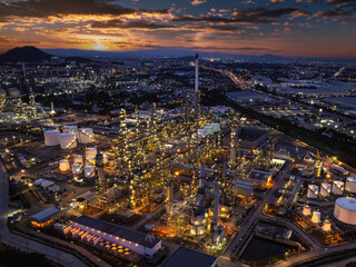 Obraz premium Oil refinery plant industry factory zone, oil and gas petrochemical industrial, oil storage tank and pipeline steel, twilight scene and over lighting equipment and the sunset and cloud sky background,