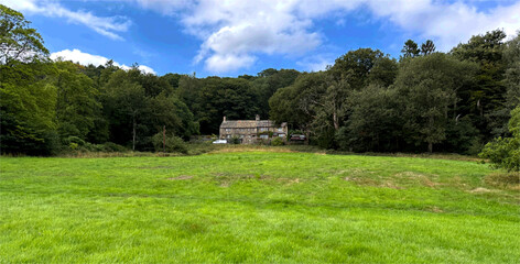 A country house rests in the shade of late summer trees, fields aglow with fading green, under a sky of gentle drift. Harden, Bingley, UK.