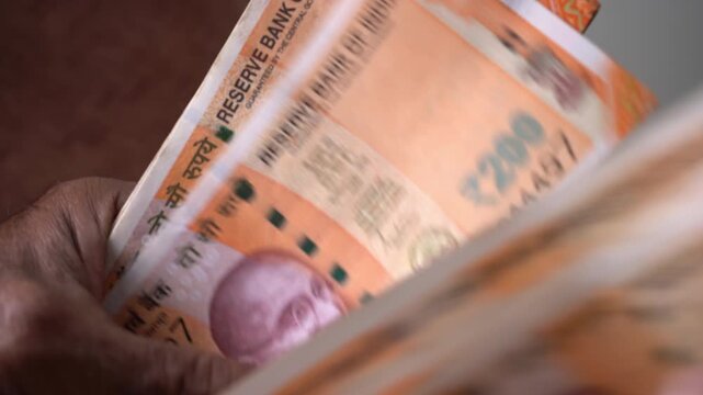 Close up hand of Indian Man Counting 200 Rupee Currency Notes
