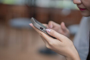 Asian girl using smartphone, reading social media, typing text or shopping online.