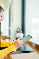 Smiling young Asian student wearing headphones talking on online chat using laptop. 
