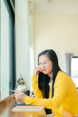 Smiling young Asian student wearing headphones talking on online chat using laptop. 