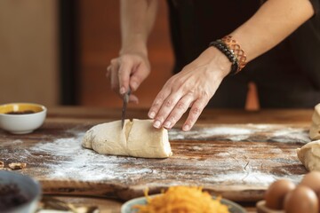 A person uses a knife to slice dough on an Oak surface dusted with flour. Bowls of fillings and eggs sit nearby, promising a delicious outcome in the kitchen
