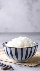 A rustic wooden table holds a deep bowl filled with fluffy white rice, steam gently rising, surrounded by traditional wooden chopsticks resting beside it.