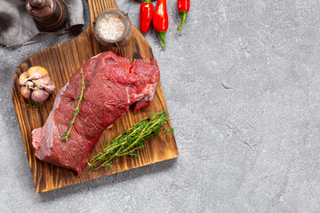 Raw beef chop on a plate. Animal product, red meat on grey background top view copy space for text