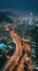 Obraz premium Cityscape at night, high-angle view. Highway curves through urban sprawl, lit by car lights. Blurred motion of vehicles. Mountains in the background. Modern buildings