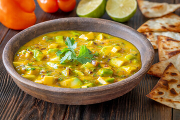 Fresh mango salsa served with tortilla chips in rustic wooden food setting