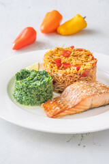 Elegant plated salmon with rice pilaf and creamy spinach on white round plate