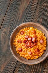 Rustic bowl of spicy tomato and chorizo risotto on wooden table