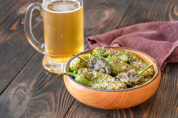 Terracotta bowl of Pimientos de Padron served with cold frothy beer
