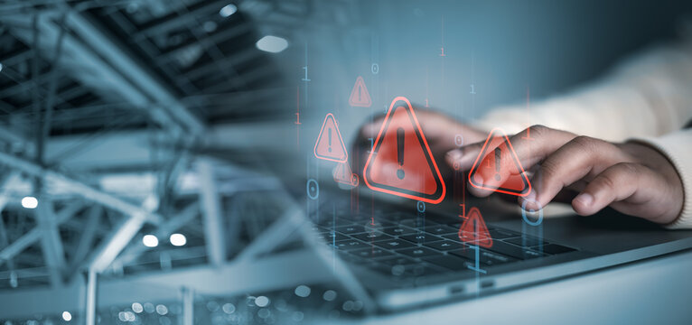 Cyber security concept, Hands typing on laptop with red cybersecurity warning icons overlay, symbolizing data breach, hacking risk, malware attack, and online security threat in digital network.
