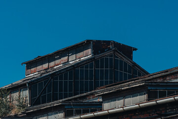 Old Industrial Factory Roof with Rusted Windows under Clear Blue Sky