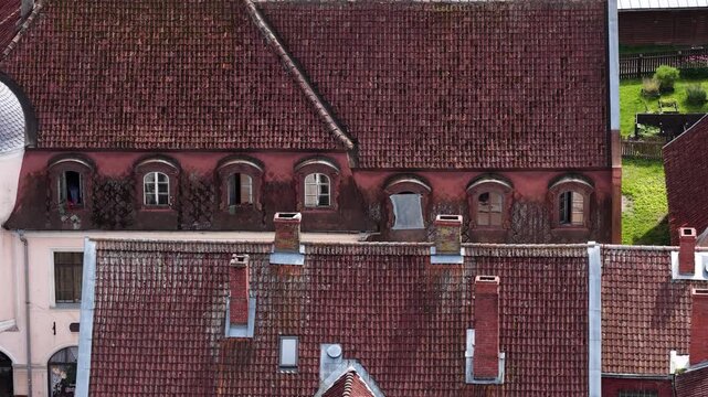 Close-up aerial view of weathered red-tiled rooftops and ornate dormer windows in Kuldiga, Latvia, showcasing aged textures and traditional European architectural charm.