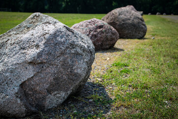 boulder rocks arranged in a linear fashion, used for landscaping, as a barrier, or a decorative element. urban or town bollards in a parking lot © mailcaroline