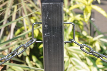 Chain link fence. A metal pole has a chain attached to it. The chain is connected to a metal post