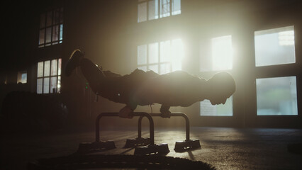 Determined athlete performing intense handstand push-ups on parallel bars in dramatic gym setting