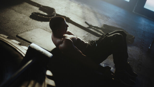 Muscular athlete performing sit-ups in dramatic gym setting - Powered by Adobe