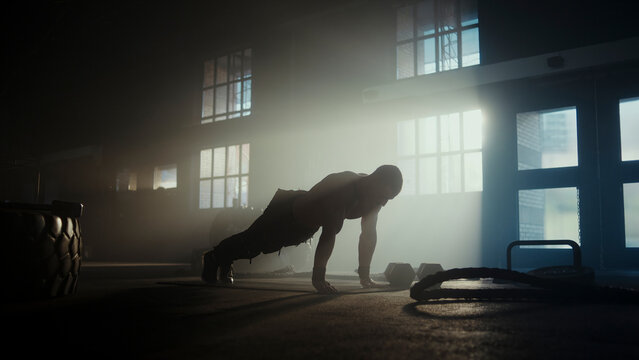 Determined athlete doing push-ups in dramatic gym setting - Powered by Adobe