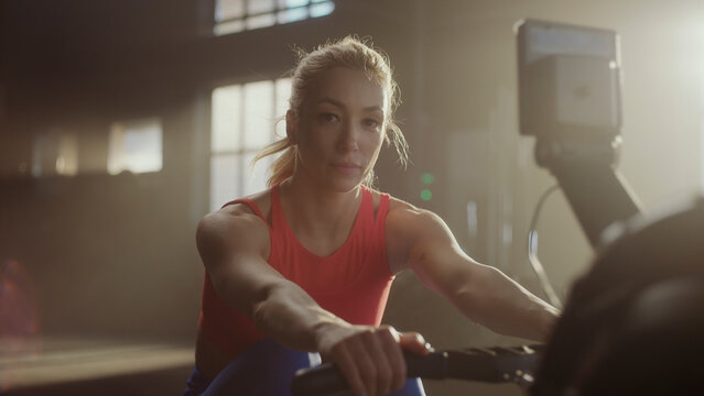 Determined athlete training on rowing machine in gym - Powered by Adobe