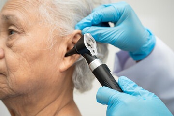 Otolaryngologist or ENT physician doctor examining senior patient ear with otoscope, hearing loss problem.