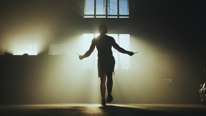 Boxer training using jump rope in dark gym