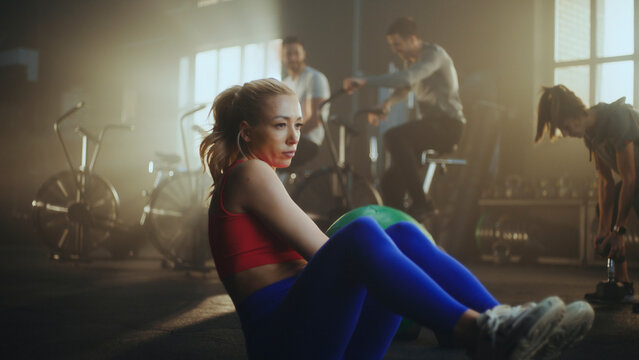 Determined sportswoman performing crunches with medicine ball in gym