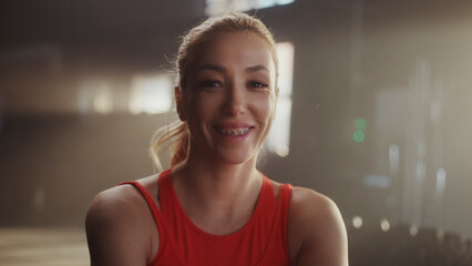 Portrait of smiling sportswoman with braces posing in gym after workout