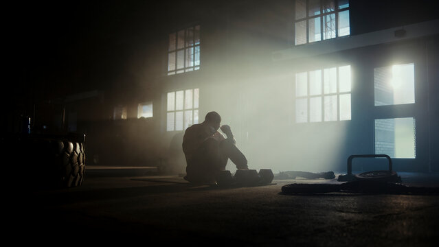 Tired athlete resting after intense workout in industrial gym