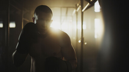 Boxer training with boxing gloves in a gym with dramatic lighting