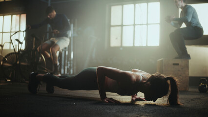Athletes training together doing push-ups, cycling and box jumps in cross training gym