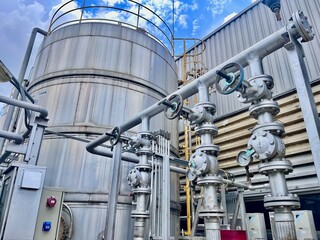 A large industrial water tank and a complex network of stainless steel pipes and valves, showcasing a sophisticated system for fluid management in a factory or plant.