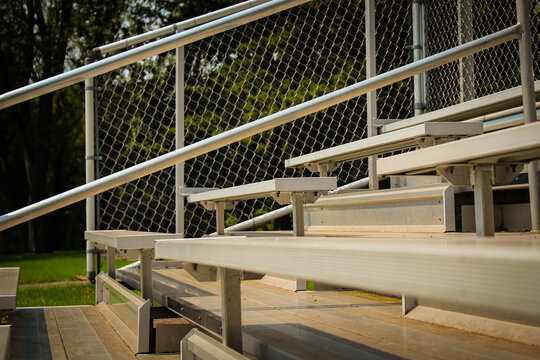 aluminum raised step fan bleachers at a sporting event or field. athletic design element, banner, or background