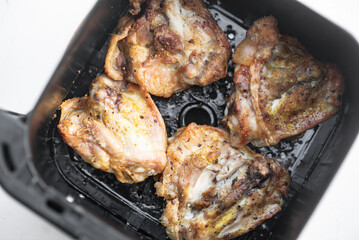 Golden brown chicken thighs cooked in air fryer basket.