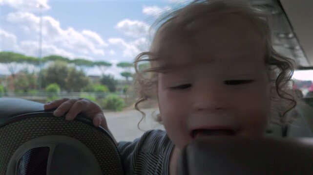 Excited toddler licks bus seat while gripping backrest, expressing impulsive curiosity and raw sensory exploration during ride on public transportation