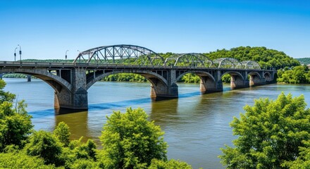 Fototapeta premium Arch bridge spans a wide river under a clear blue sky