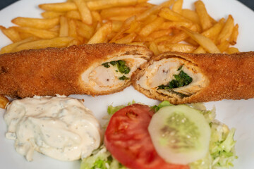 A savory rolled pancake filled with a chicken, cheese and spinach, served alongside a fresh salad and creamy dip. The perfect combination of flavors and textures, ideal for a satisfying meal