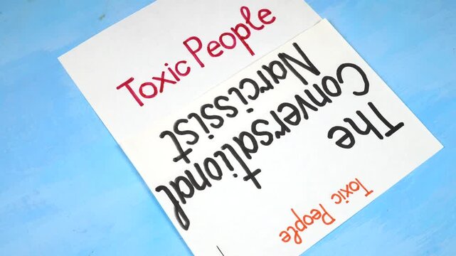 Words &ldquo;The Conversational Narcissist&rdquo; handwritten on a white sheet of paper. Sheets of paper with written theses on the topic &laquo;Toxic People&raquo; are on a blue background 