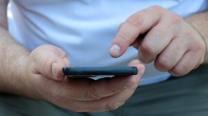 close-up of the hands of a man who is using his smartphone