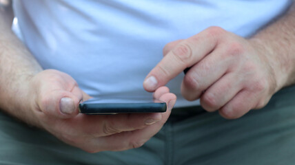close-up of the hands of a man who is using his smartphone