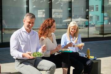 Smiling business colleagues enjoying a healthy lunch break outdoors