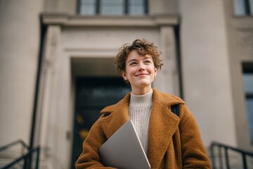 Fototapeta premium Joyful woman with laptop in front of a structure
