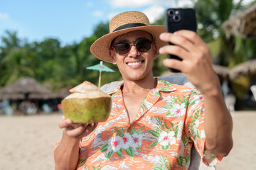 Hispanic man tourist sitting and using phone while having coconut water drink
