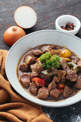 Dark Beef Stew with Onions and Parsley in Rustic Bowl