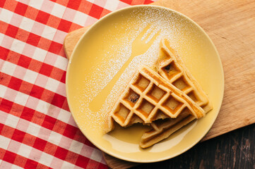 Golden Waffles with Powdered Sugar on Yellow Plate